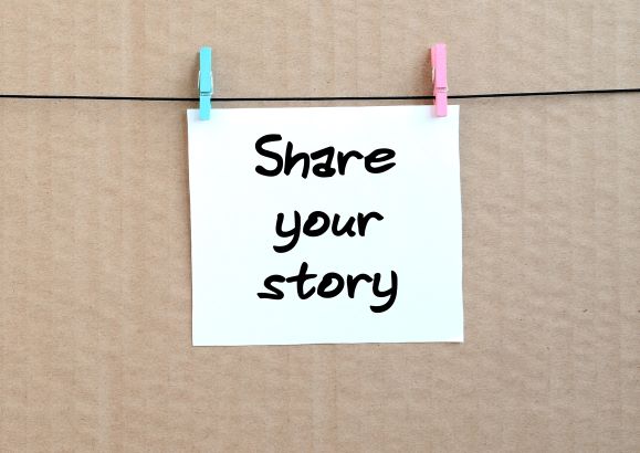 Share your Story. Schwarze Schrift auf weißem Papier.