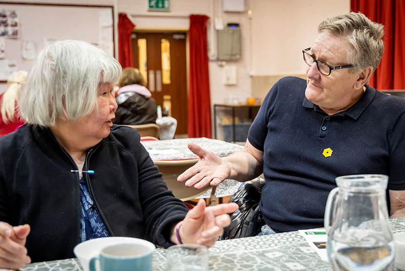 Eine ältere Dame und ein älterer Herr im Gespräch bei Kaffee und Kuchen
