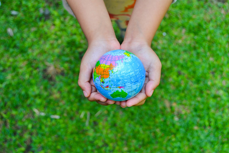 Kinderhände halten eine kleine Weltkugel