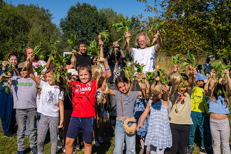 Eine Kindergruppe am WeltTrellerFeld hält stolz die Rübenernte in die Kamera.